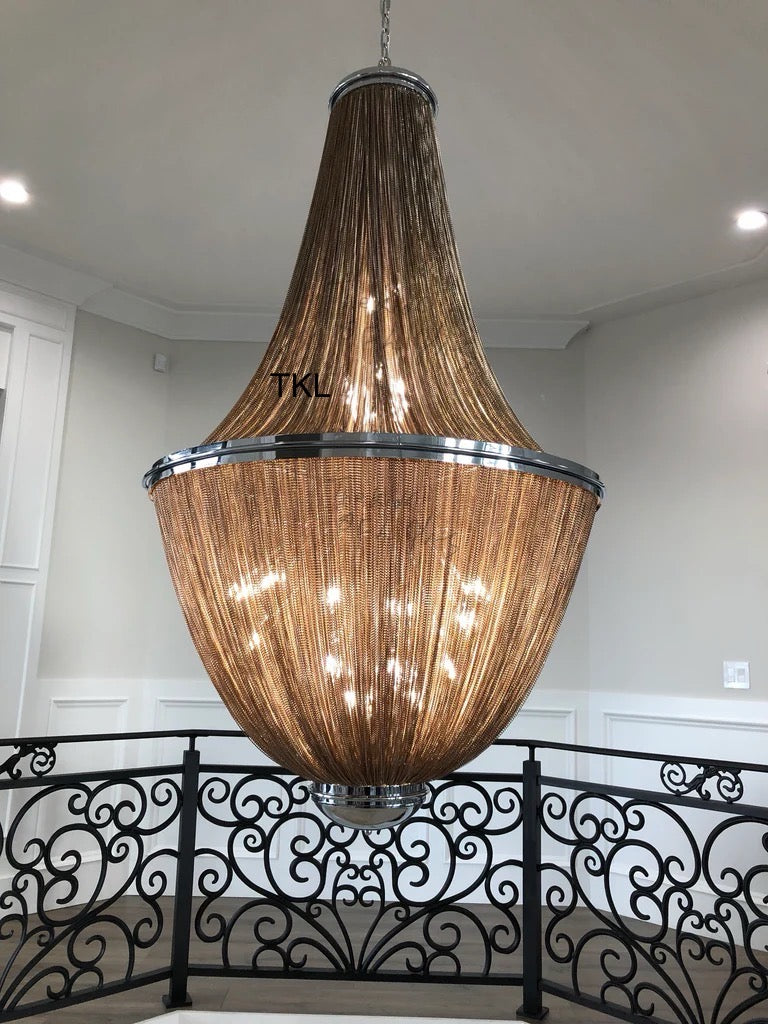Large decorative chandelier hanging in a room with a black metal railing.