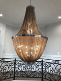 Large decorative chandelier hanging in a room with a black metal railing.